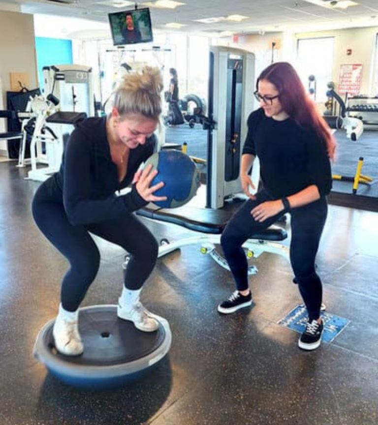 Female personal trainer coaching a client through a balance and strength exercise on a BOSU ball at Women's Fitness Clubs of Canada, focused on form, confidence, and results.