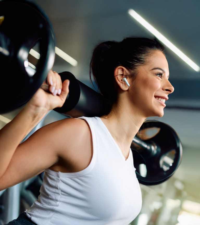 Smiling woman lifting a barbell at Women's Fitness Clubs of Canada, building strength and confidence in a supportive, women-only training environment.