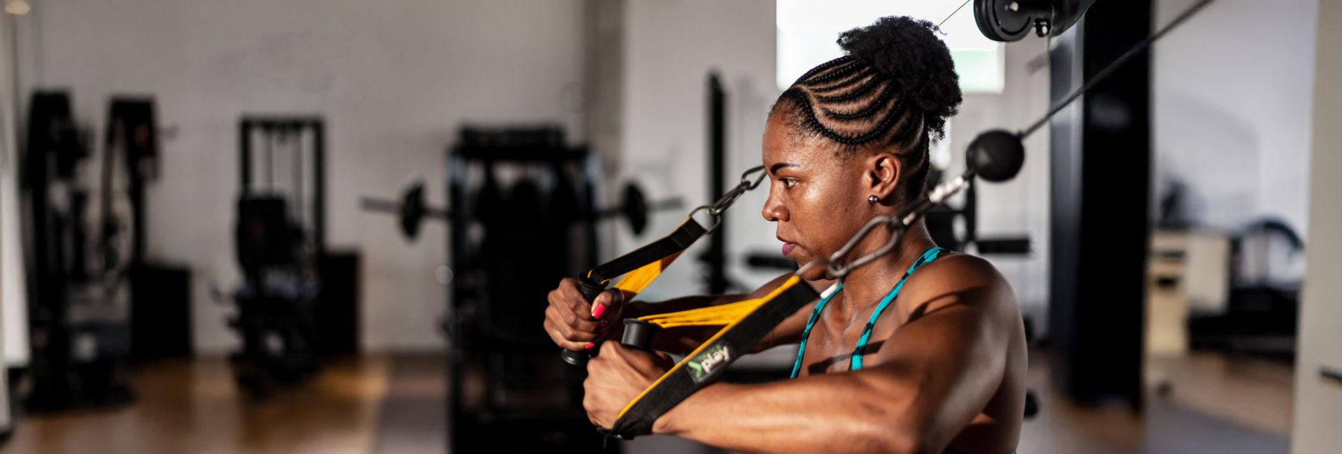 Woman performing strength training on cable machine at Women's Fitness Clubs of Canada gym, highlighting upper body workout and fitness focus.